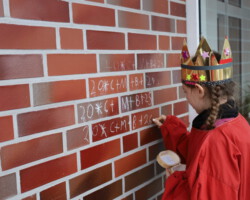 Judth schreibt den Segen an die Hauswand. (Foto: Jens Völker)